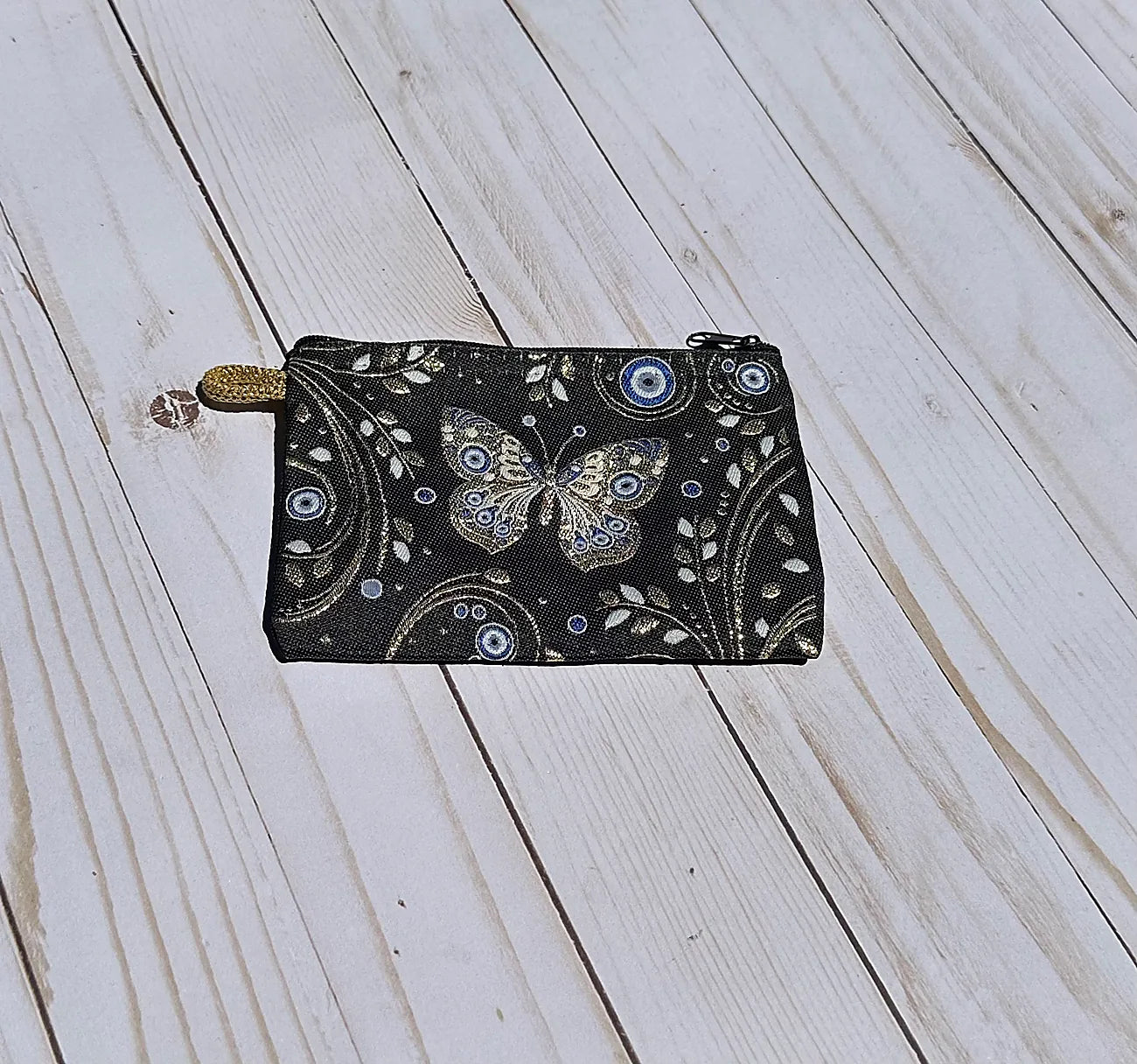 Black pouch with butterfly design on a wooden surface