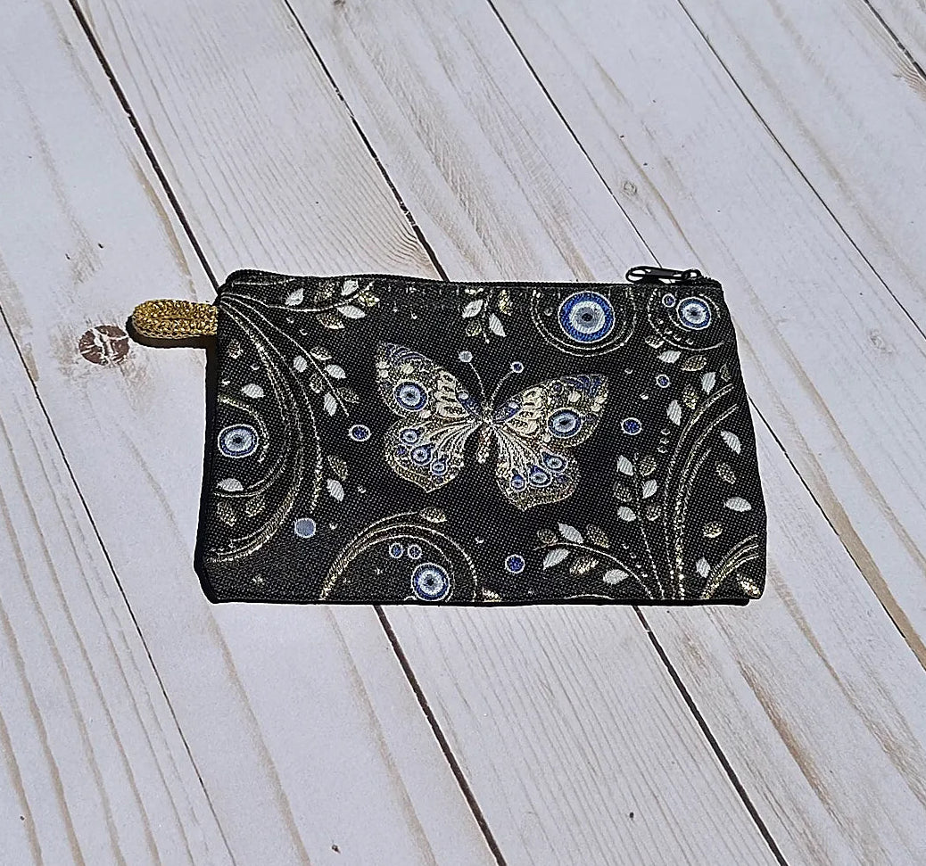 Black pouch with butterfly design on a wooden surface