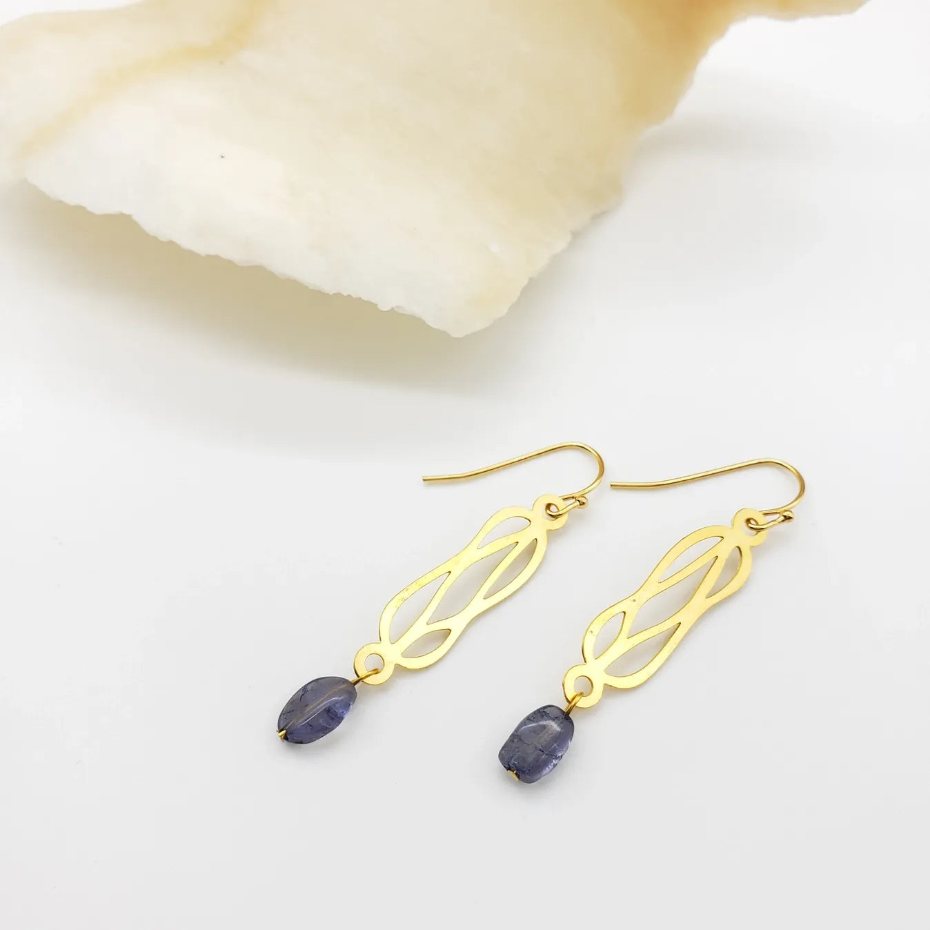 Gold earrings with purple stones on a white background