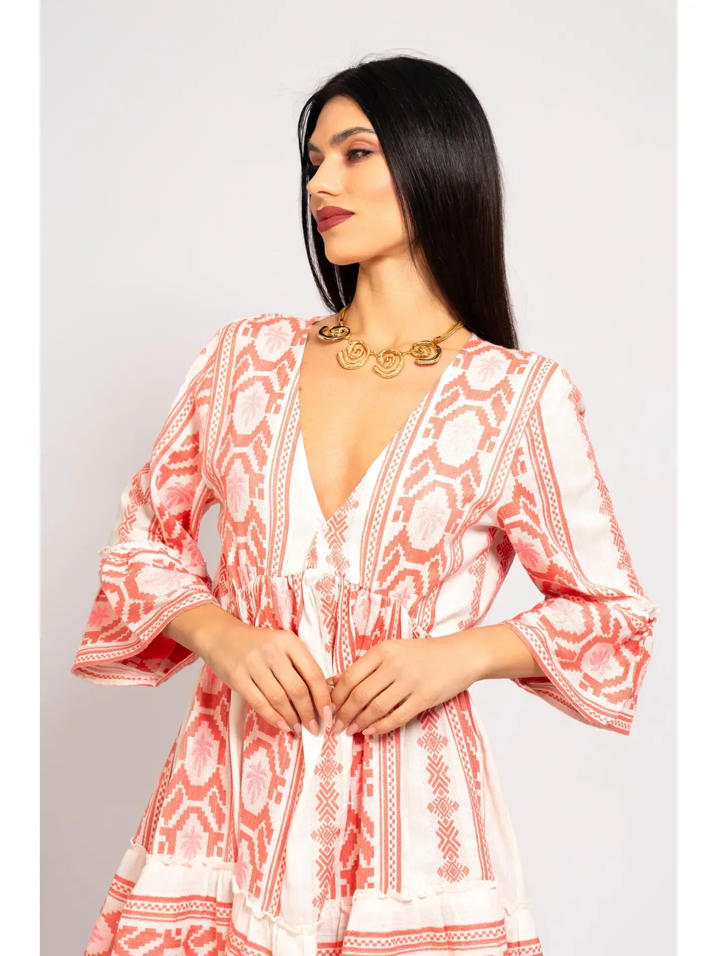 Woman wearing a pink and white patterned dress against a plain background