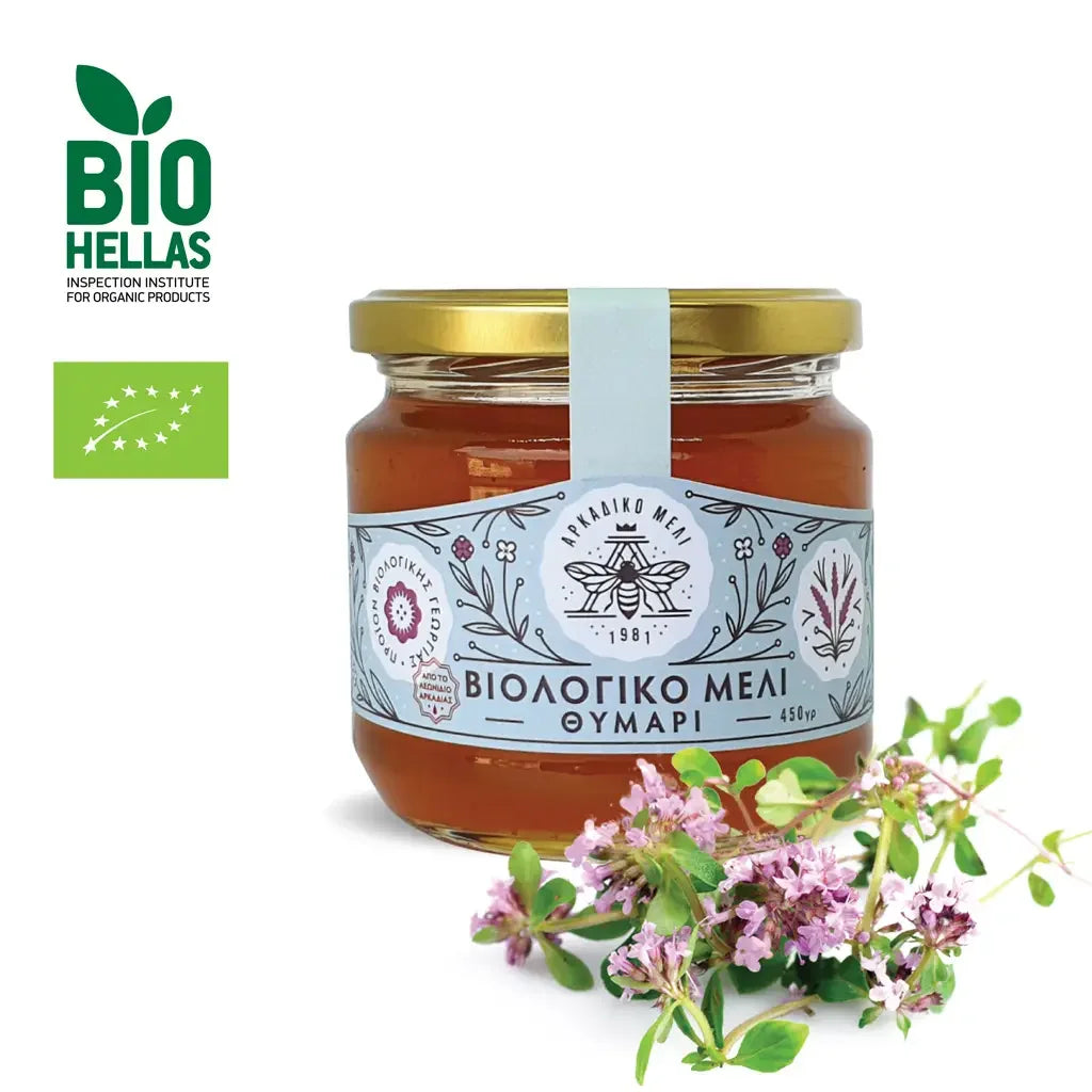 Jar of honey with a label and flowers on a white background, featuring the Bio Hellas logo