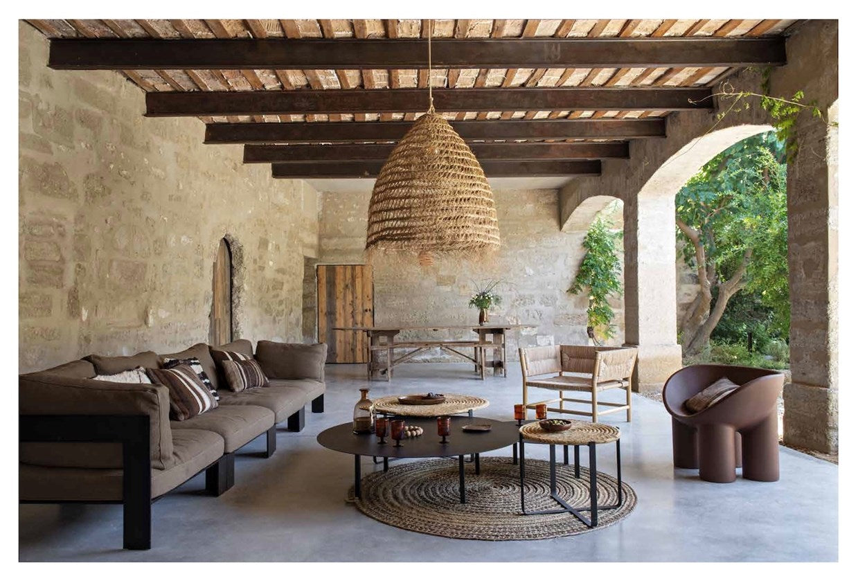 Modern living room with stone walls, wooden beams, and decorative furniture.