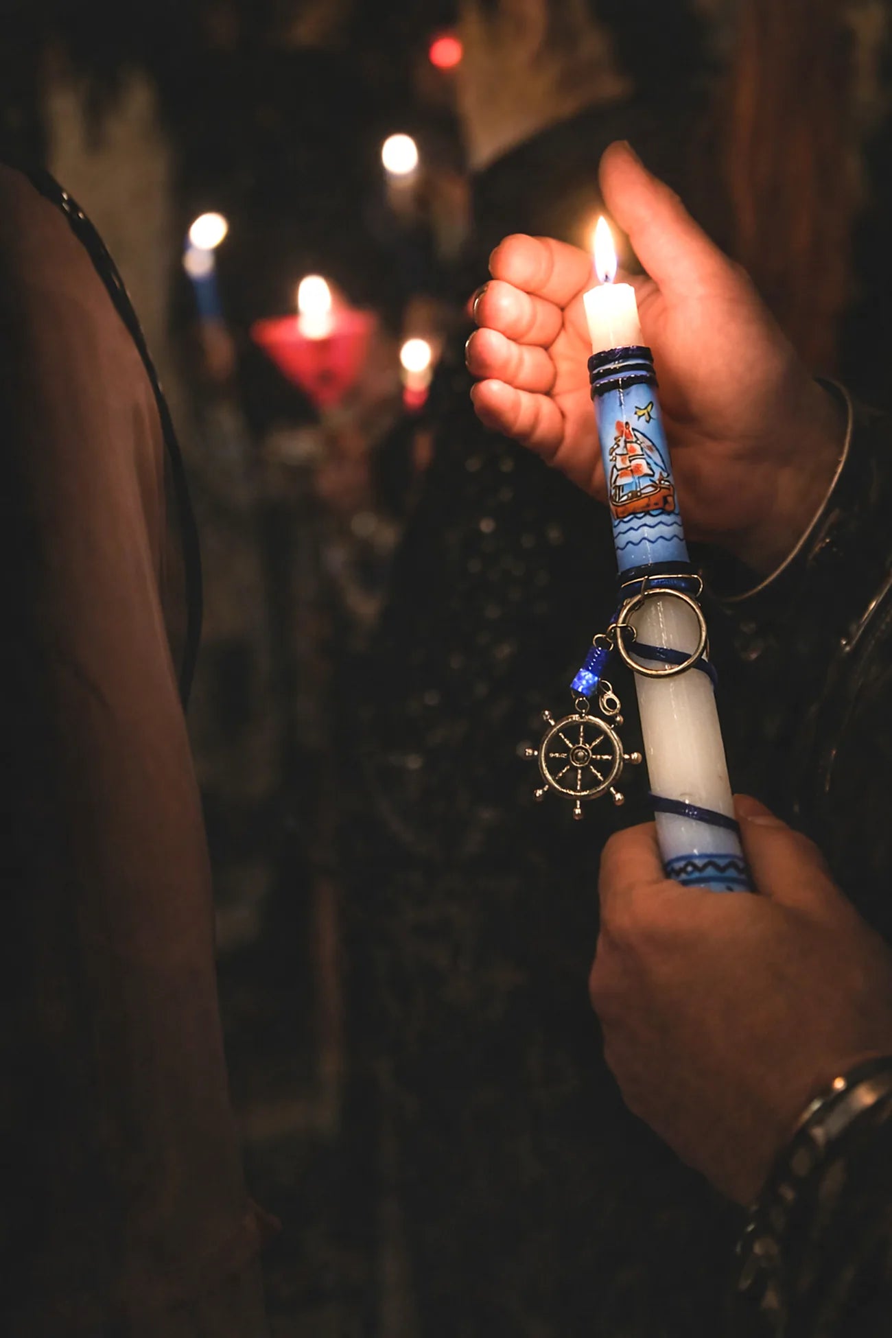 Hand holding a decorated candle with blurred lights in the background