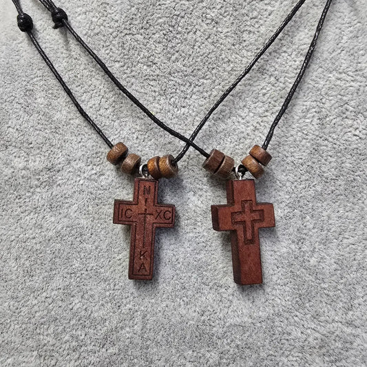 Two wooden cross necklaces with beads on a textured surface