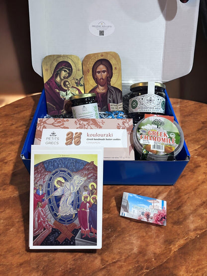 Box of Greek food products including jam, cookies, and a card on a wooden surface.