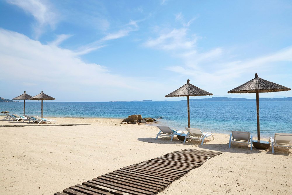 Beach scene with lounge chairs and umbrellas under a clear blue sky