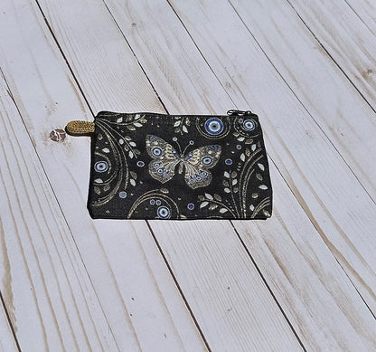 Black pouch with butterfly design on a wooden surface