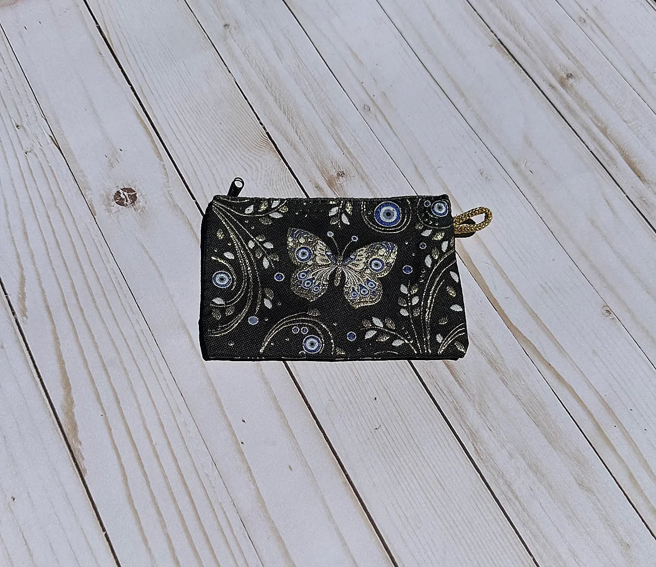 Black pouch with butterfly design on a wooden surface