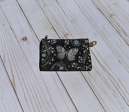 Black pouch with butterfly design on a wooden surface
