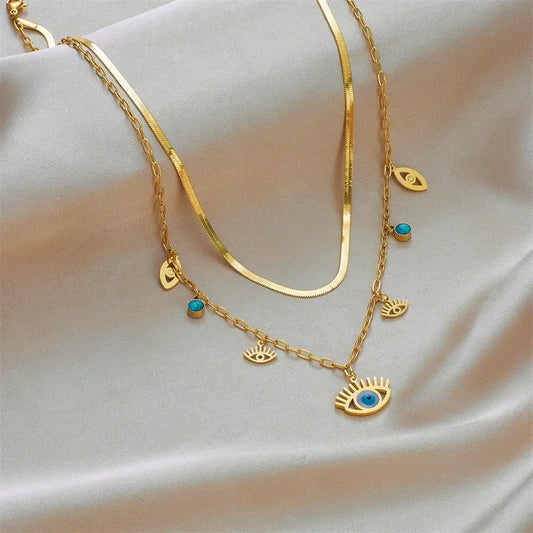 Gold necklace with eye-shaped charms on a soft fabric background