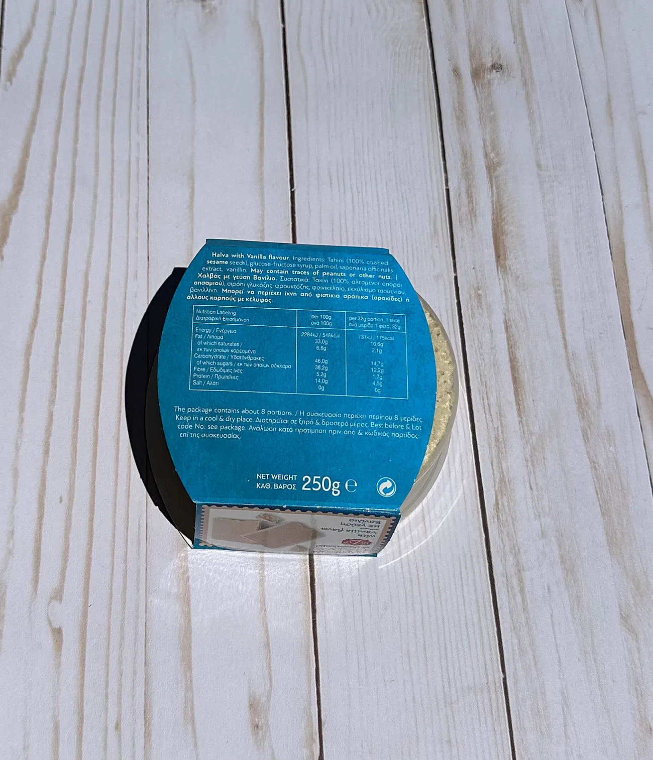 Blue label on a round product with text and symbols, placed on a wooden surface.