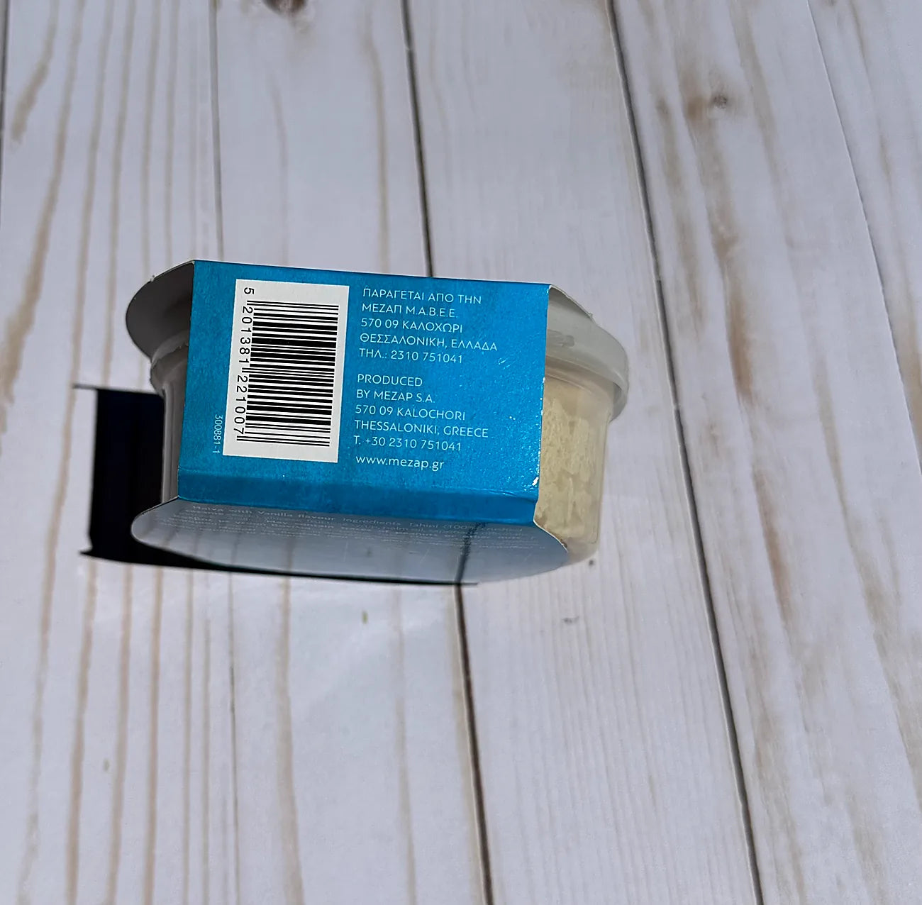 Cylindrical container with blue label on a wooden surface