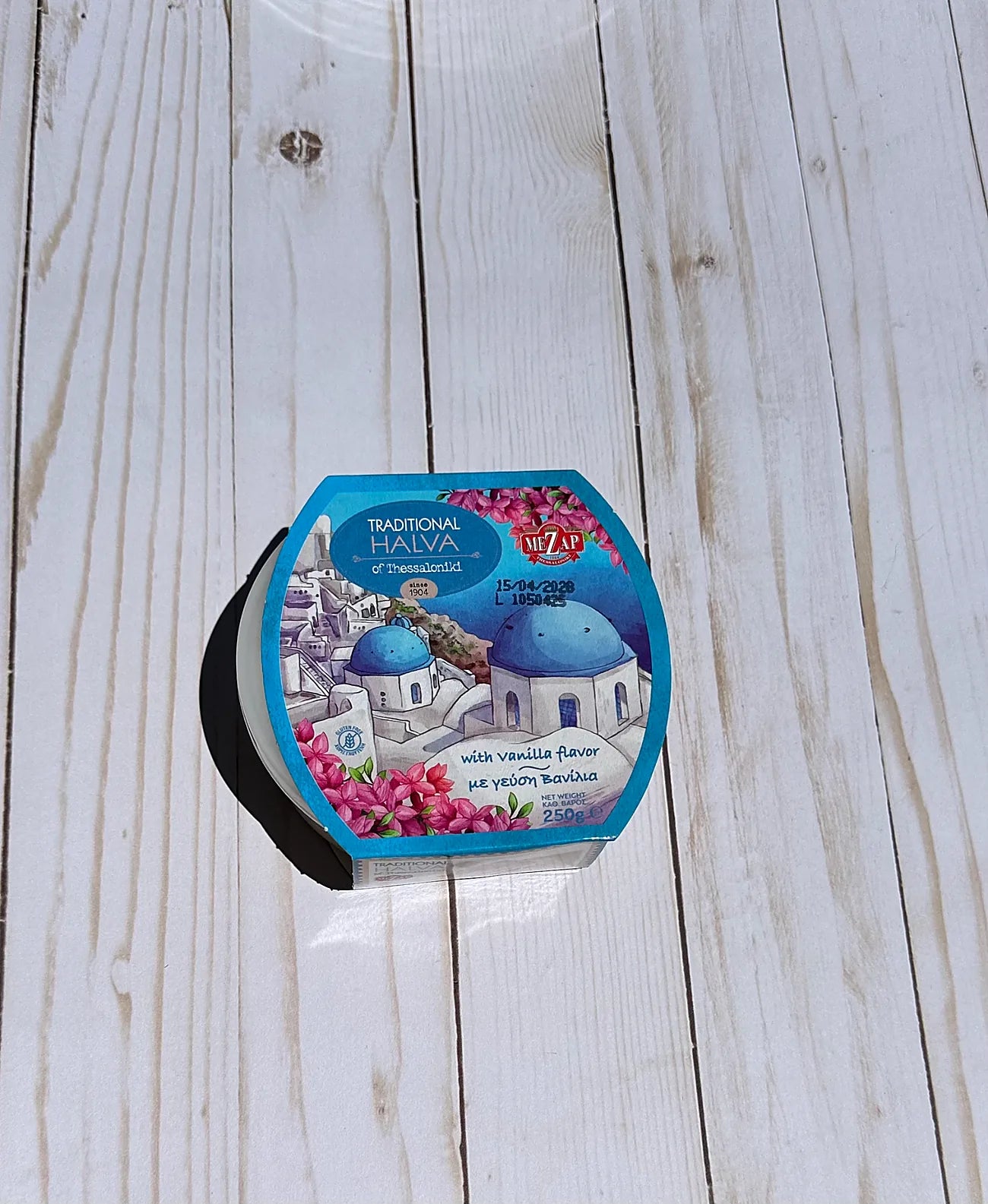 Hexagonal container of halva with a colorful label on a wooden surface