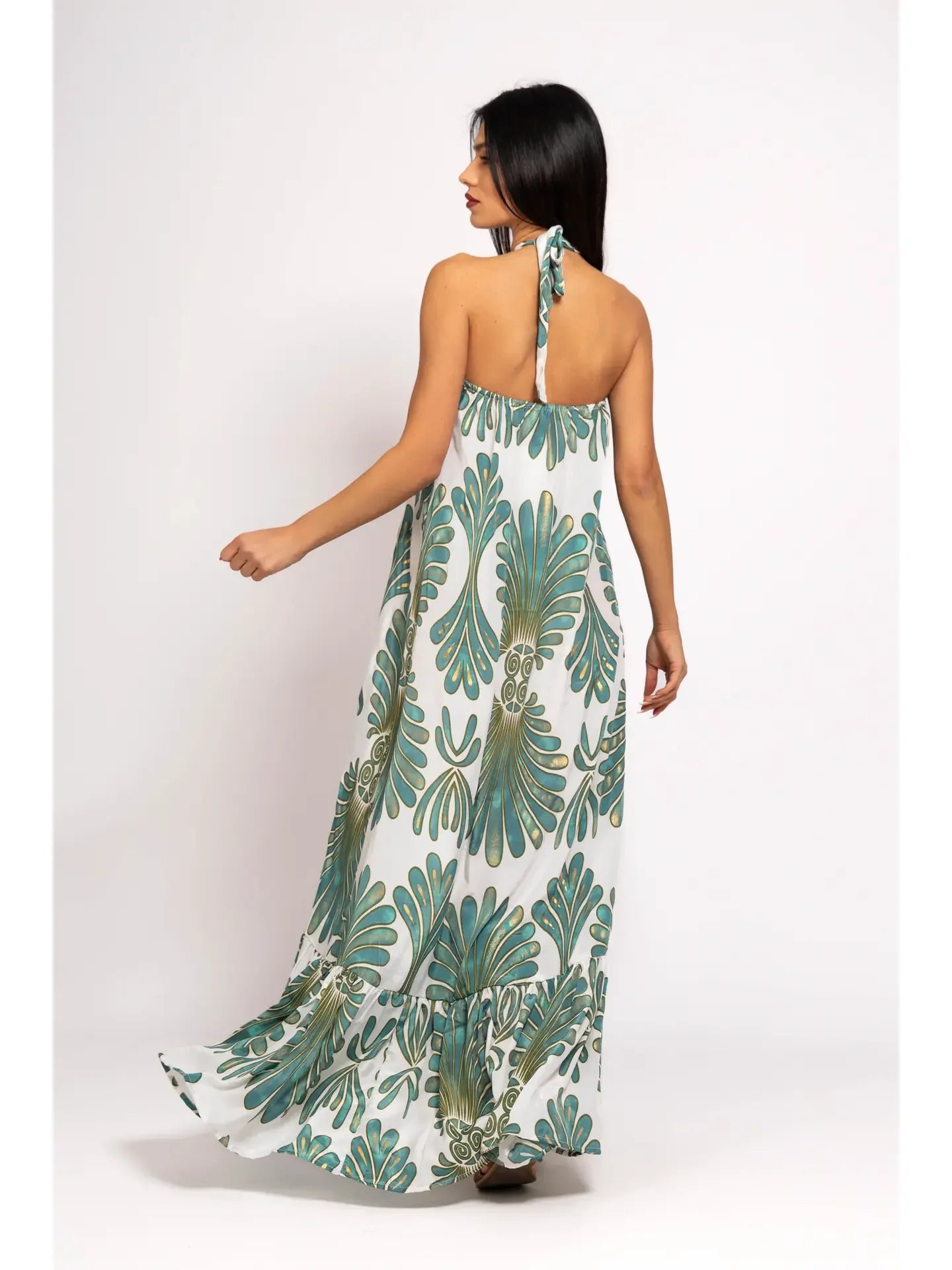 Woman wearing a long, patterned dress with green leaf design on a white background