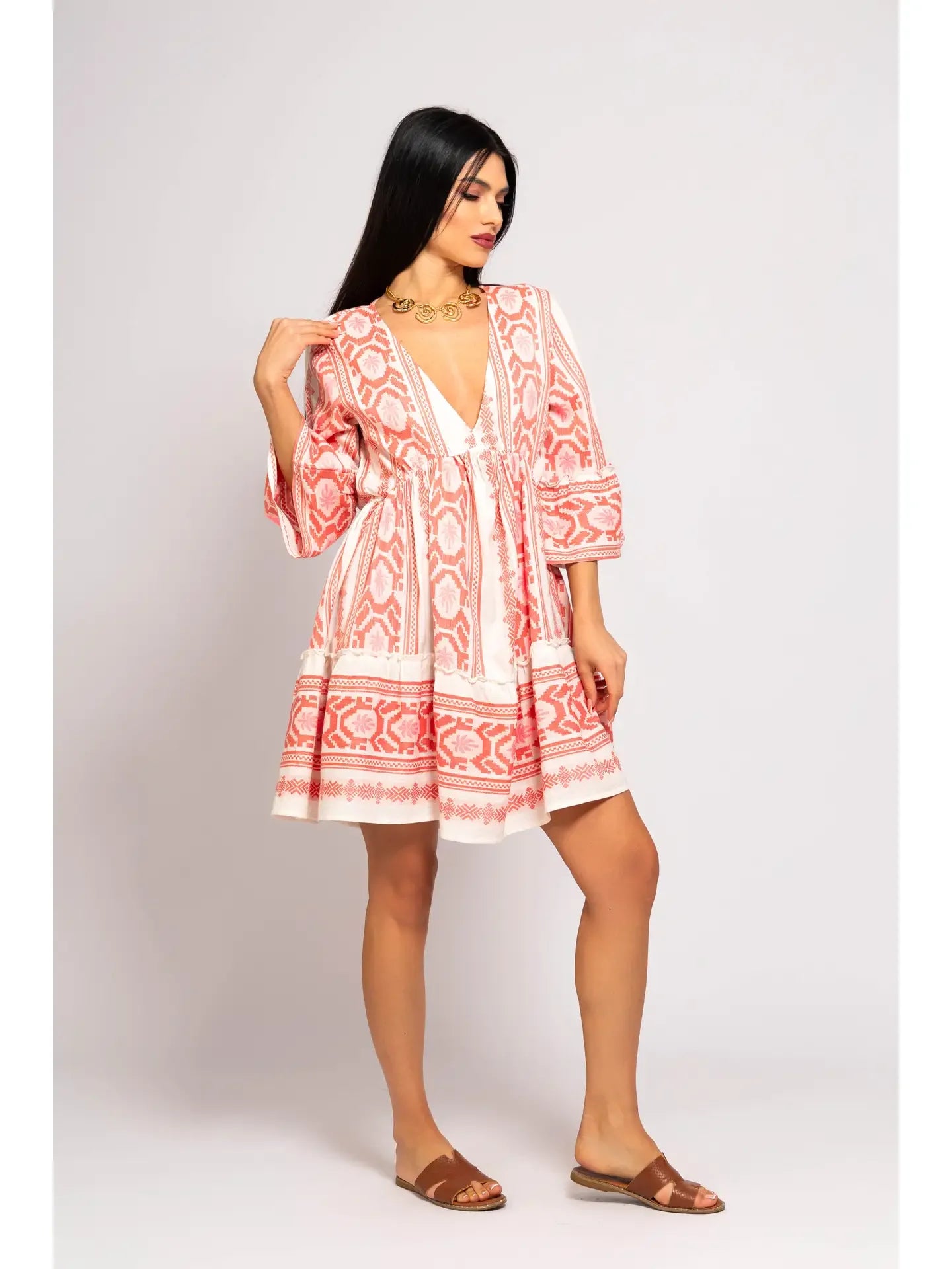 Woman wearing a red and white patterned dress on a plain background - front right view
