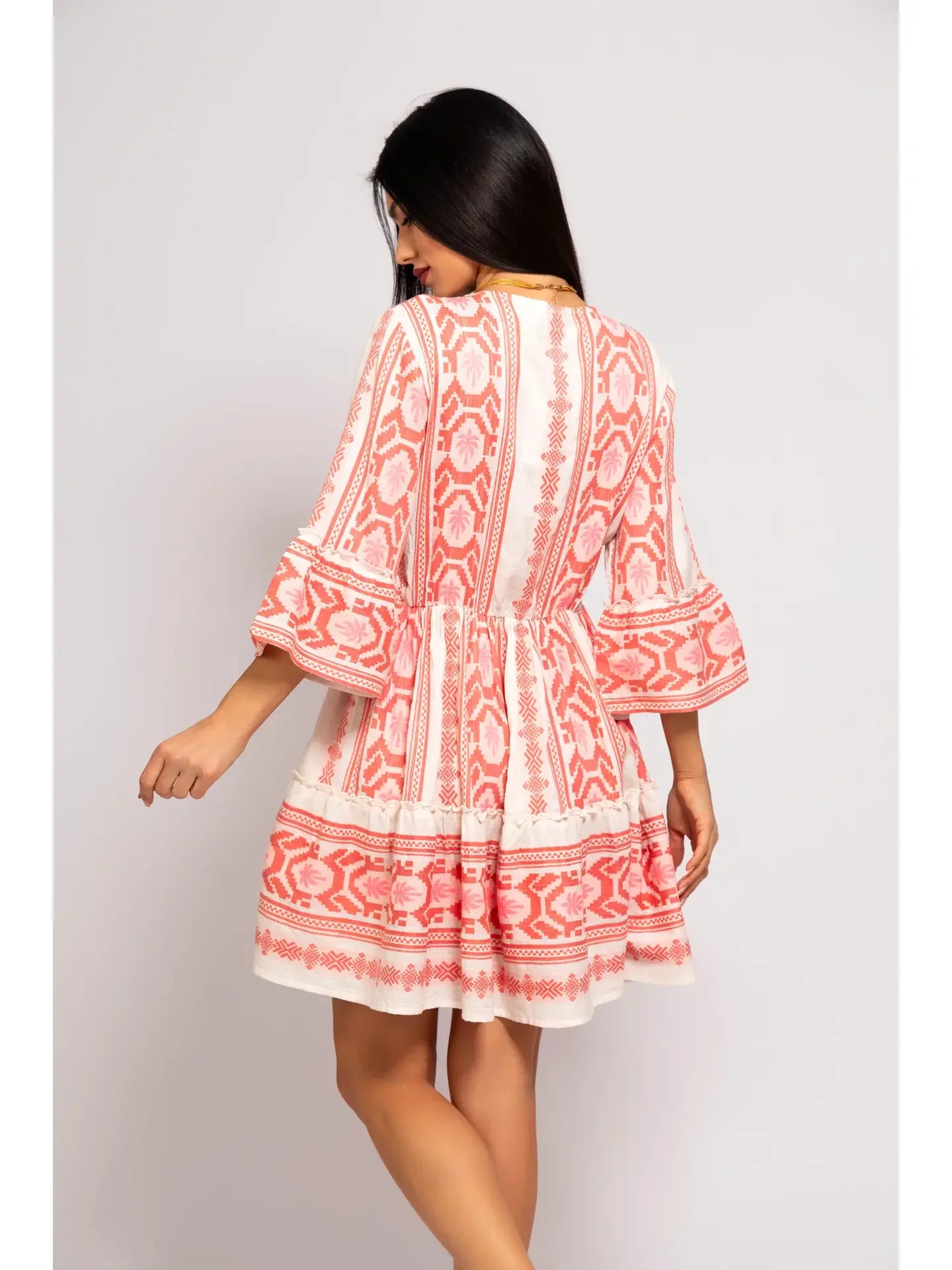 Woman wearing a red and white patterned dress on a plain background - view of back