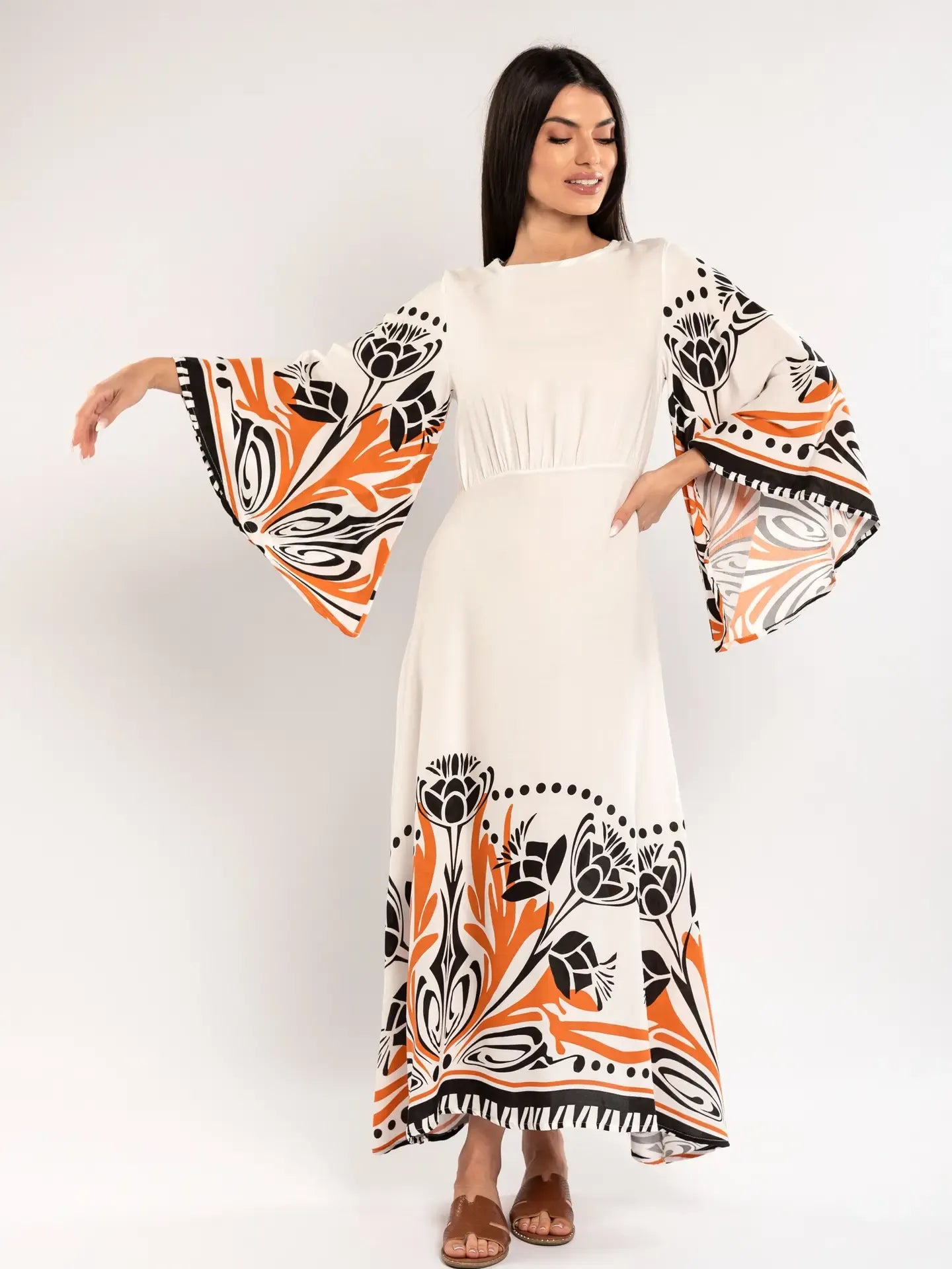 Woman wearing a white dress with orange and black floral patterns on a white background
