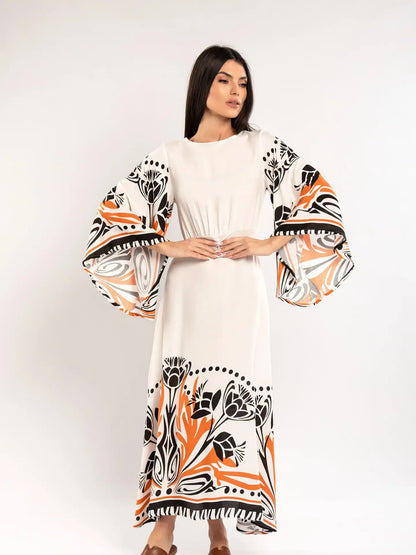 Woman wearing a white dress with black and orange floral patterns on a plain background