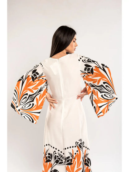 Woman wearing a white dress with orange and black floral patterns on a plain background