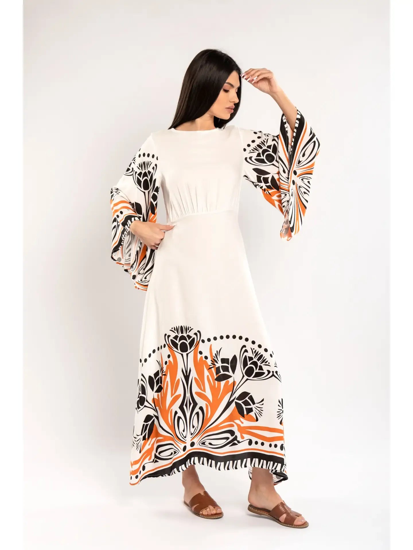 Woman wearing a white dress with black and orange floral patterns on a white background