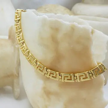 Gold necklace with intricate Greek Key Meander design on a shell background