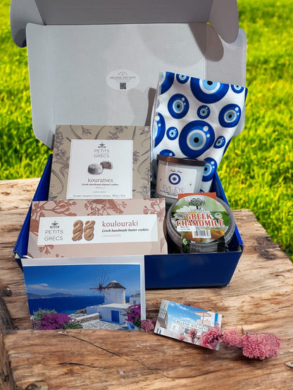 Gourmet gift box with Greek-themed items on a wooden surface with grass in the background