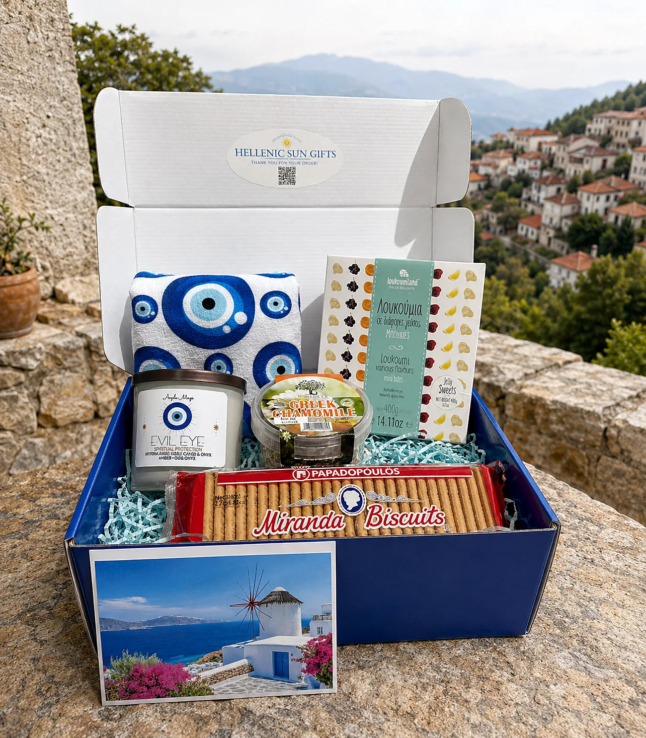 Gift box with Greek-themed products against a scenic background
