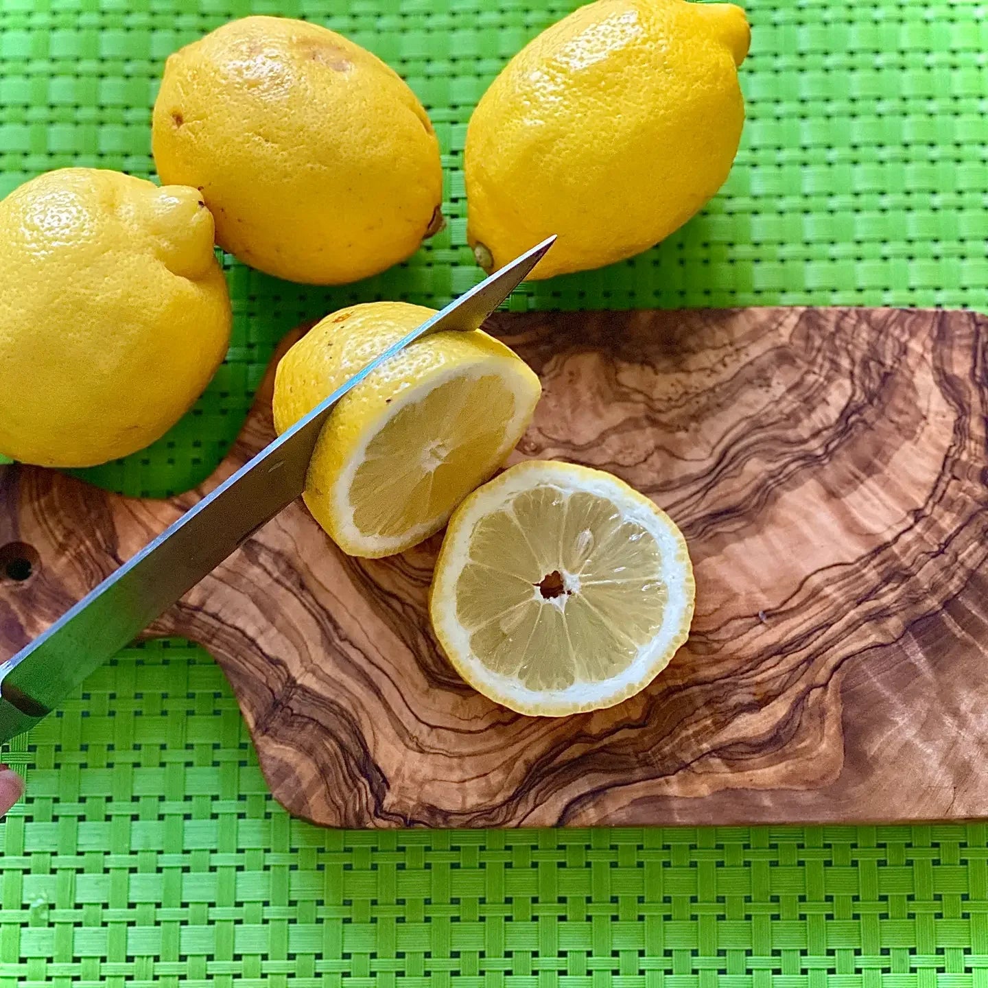 Lemons on a wooden cutting board with a knife, on a green mat