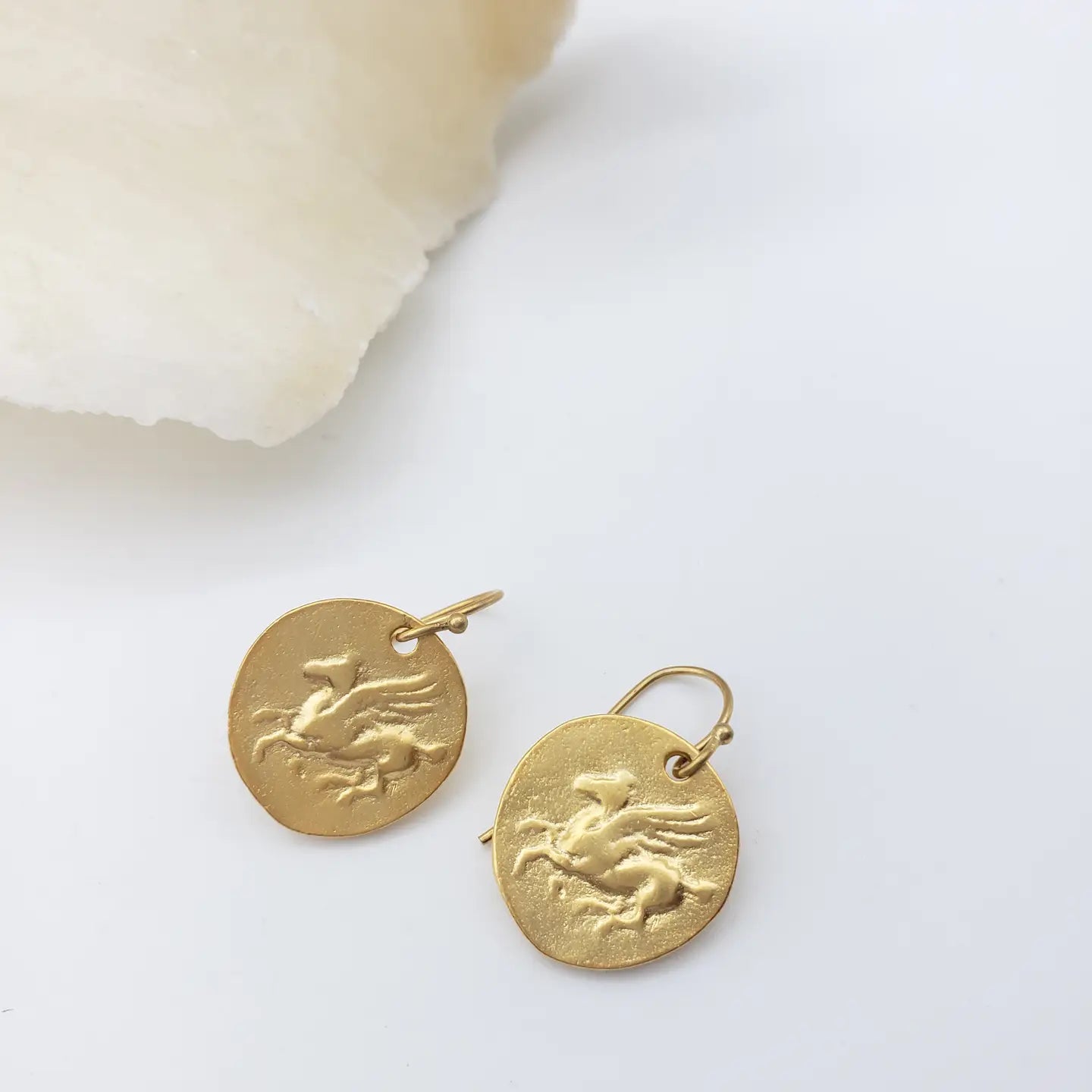 Gold Pegasus earrings with a design on a white background