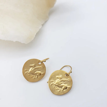 Gold Pegasus earrings with a design on a white background