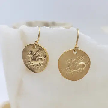 Gold Pegasus earrings with engraved designs on a white surface