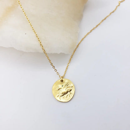 Gold necklace with a round Pegasus pendant on a light background