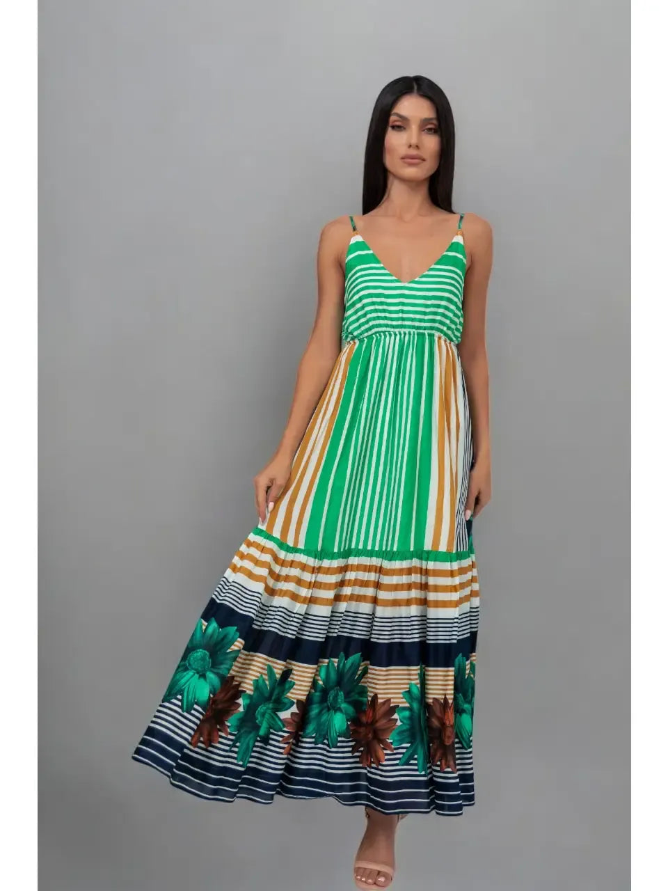 Woman wearing a green and multicolor striped dress with floral details on a gray background