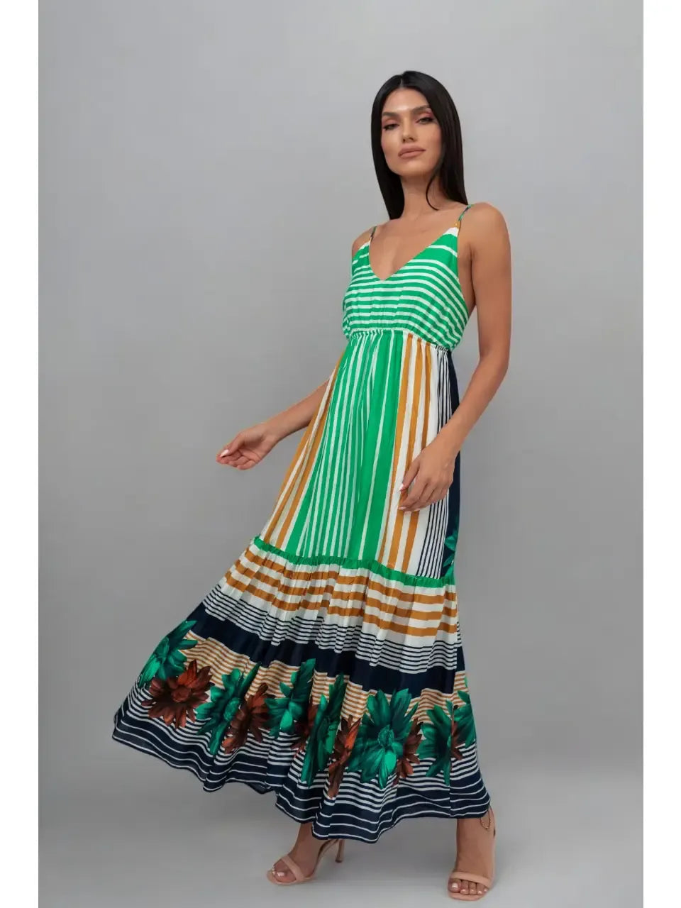 Woman wearing a green and multicolor striped dress on a gray background