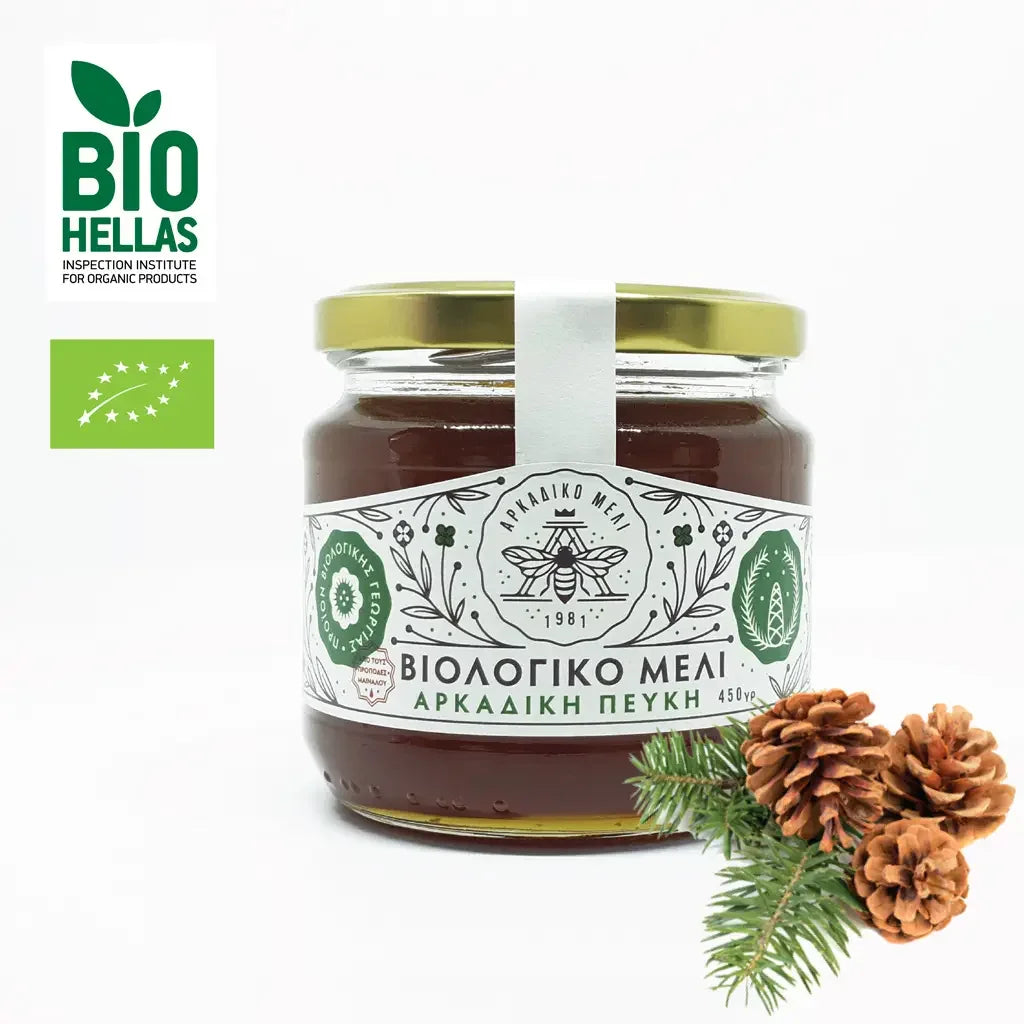 Jar of honey with a label and pine cones on a white background, featuring the Bio Hellas logo