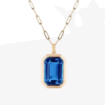 Gold necklace with a blue gemstone pendant on a white background