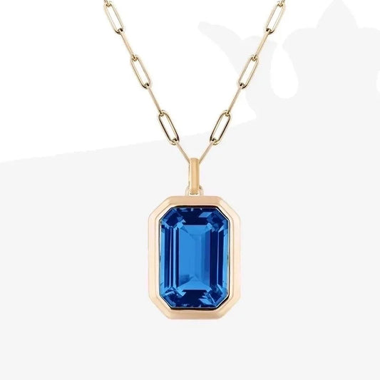 Gold necklace with a blue gemstone pendant on a white background