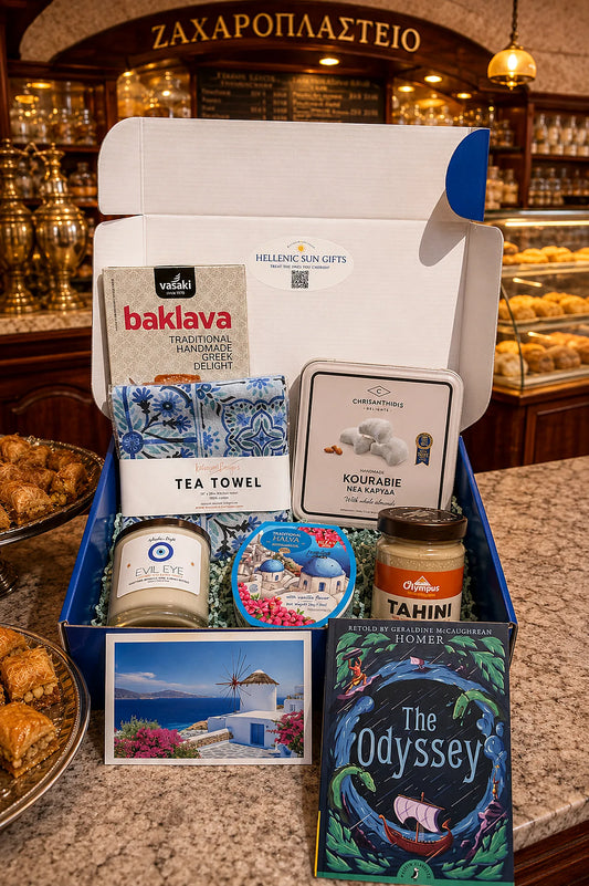 Gift box with Greek-themed items including baklava, tea towel, and book on a counter.
