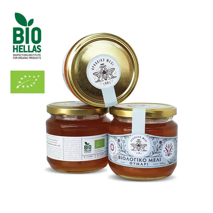 Three jars of honey with gold lids on a white background, featuring the Bio Hellas logo