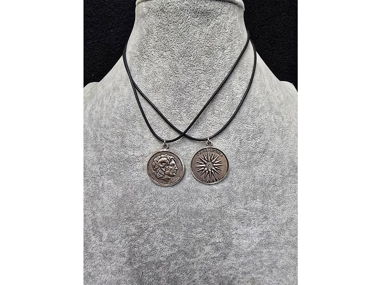 Two necklaces with circular pendants on a gray mannequin bust.