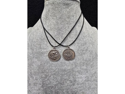 Two necklaces with circular pendants on a gray mannequin bust.