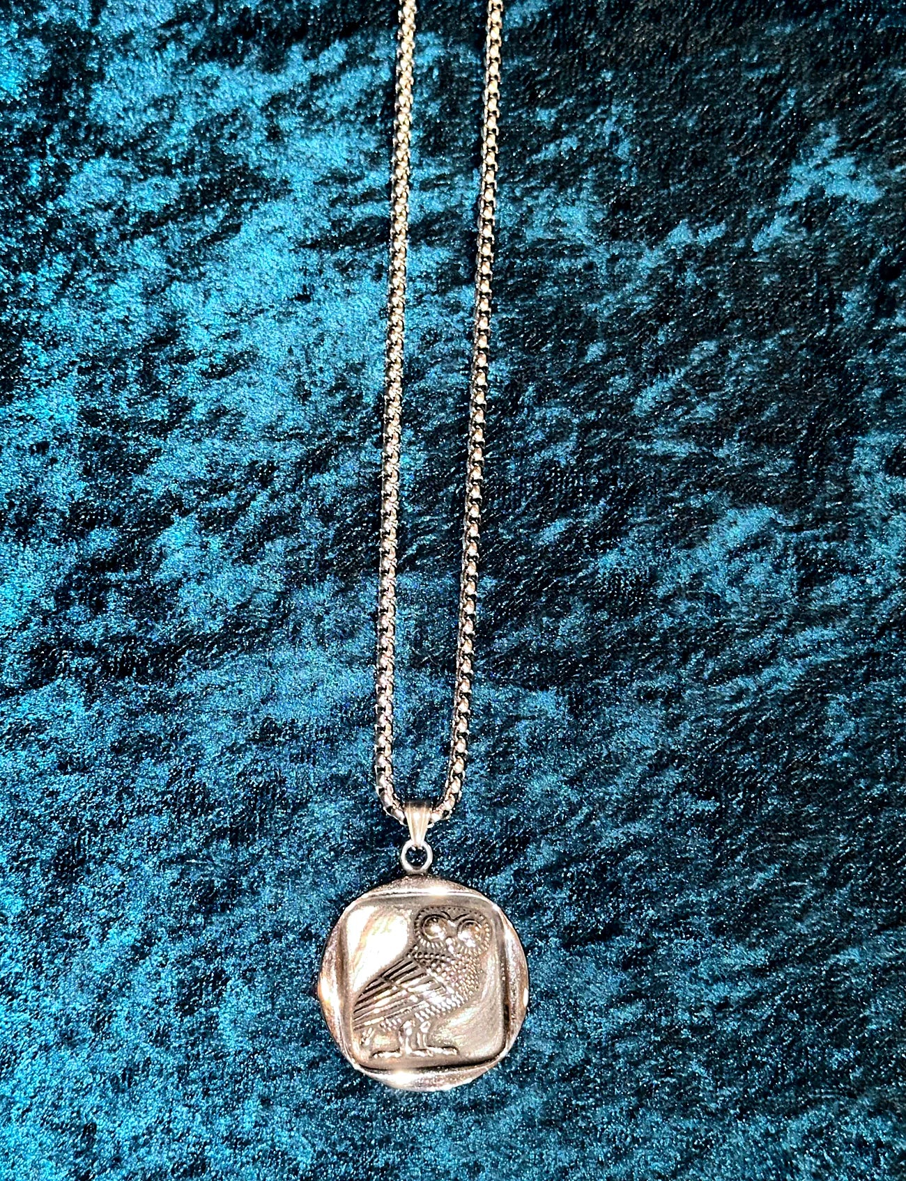 Silver necklace with a pendant on a textured blue background