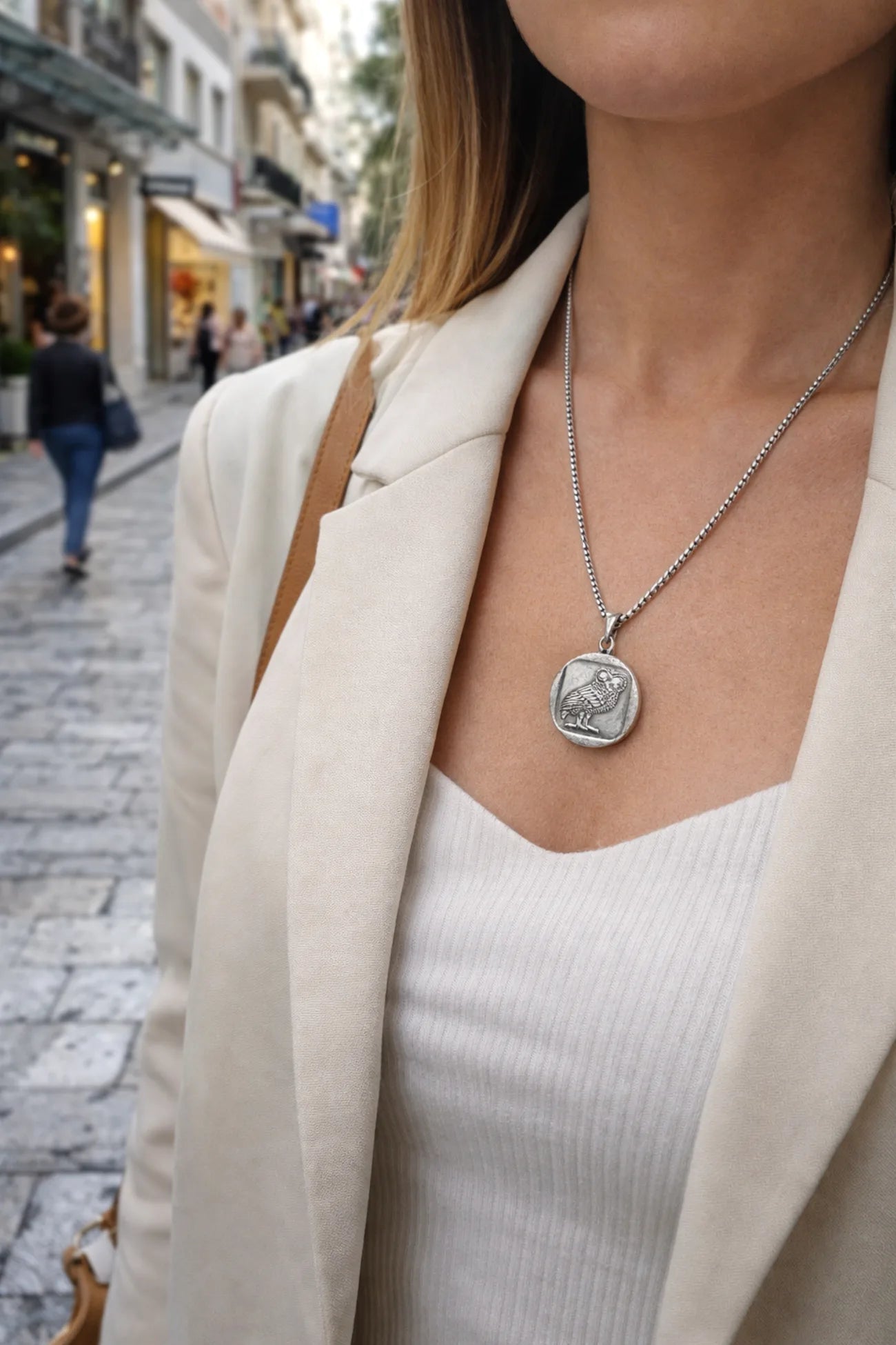 Person wearing a necklace with a pendant on a city street