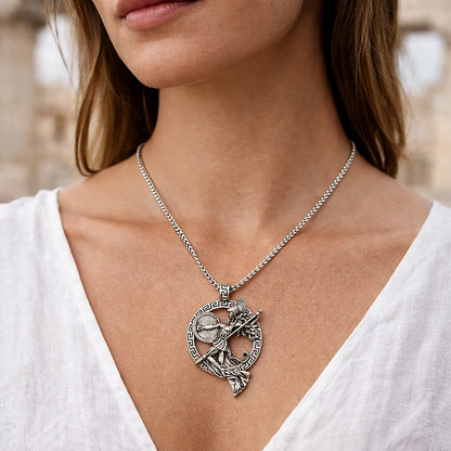 Silver necklace with a detailed pendant worn by a person in a white top.