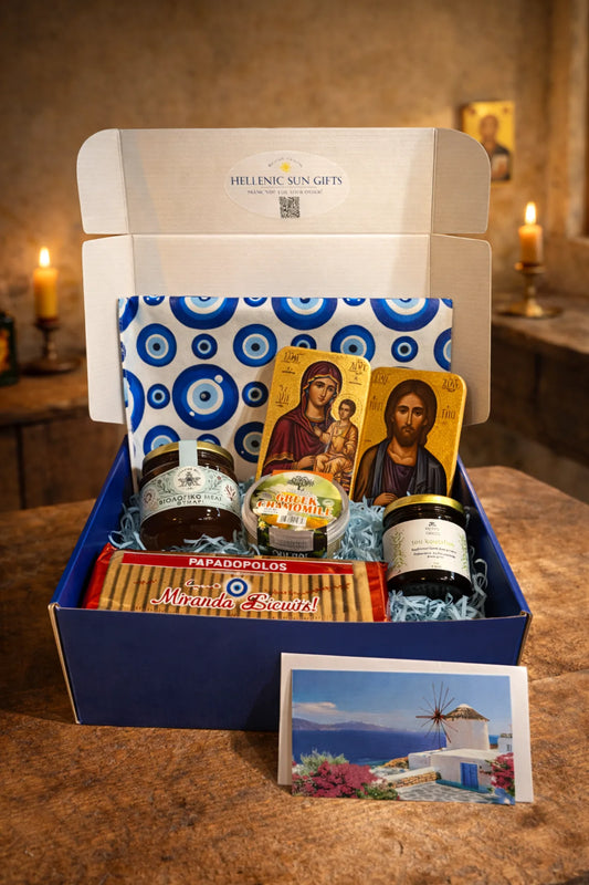 Gift box with Greek-themed products including honey and postcards on a wooden surface.