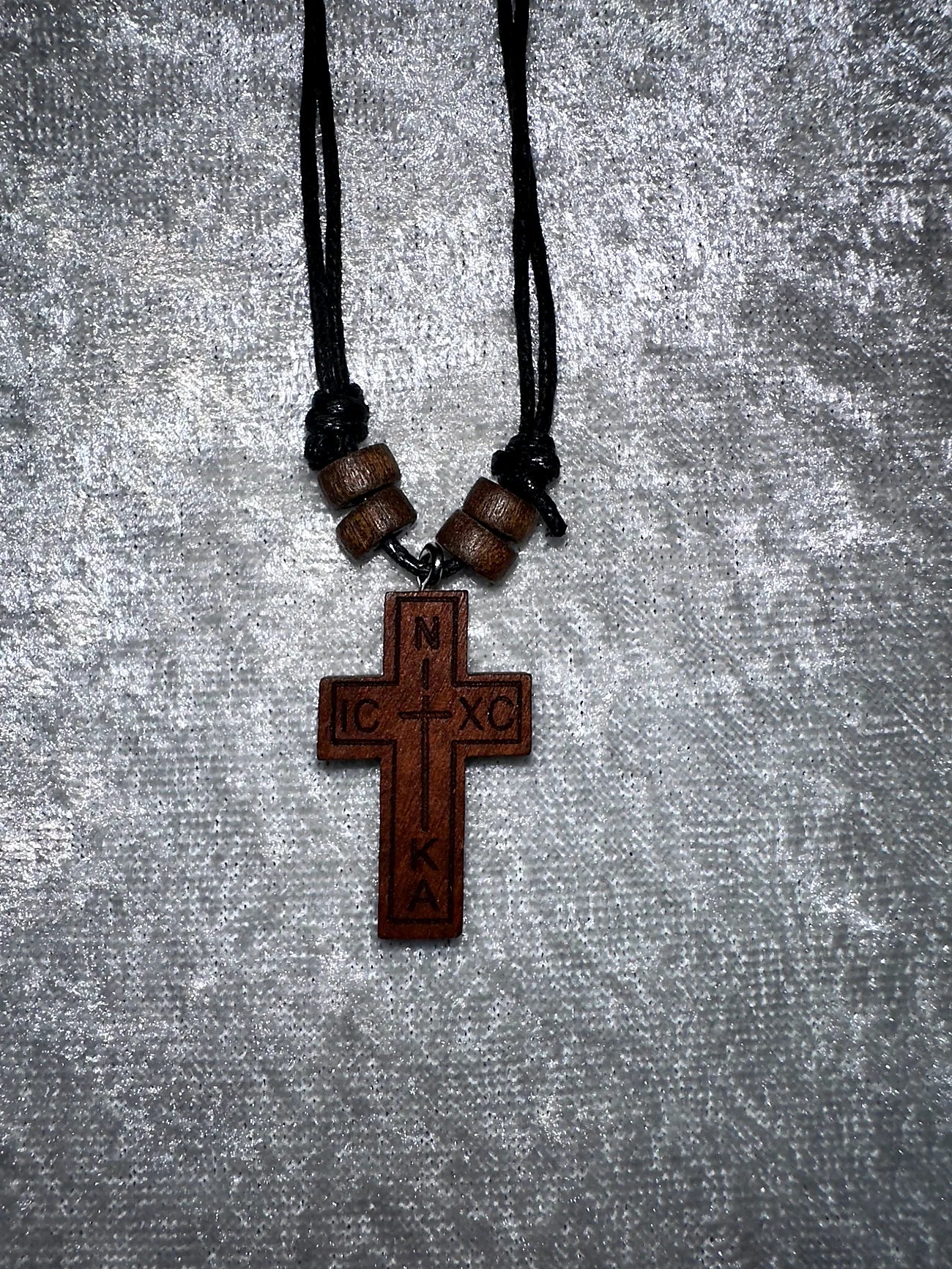 Wooden cross pendant with beads on a gray textured background