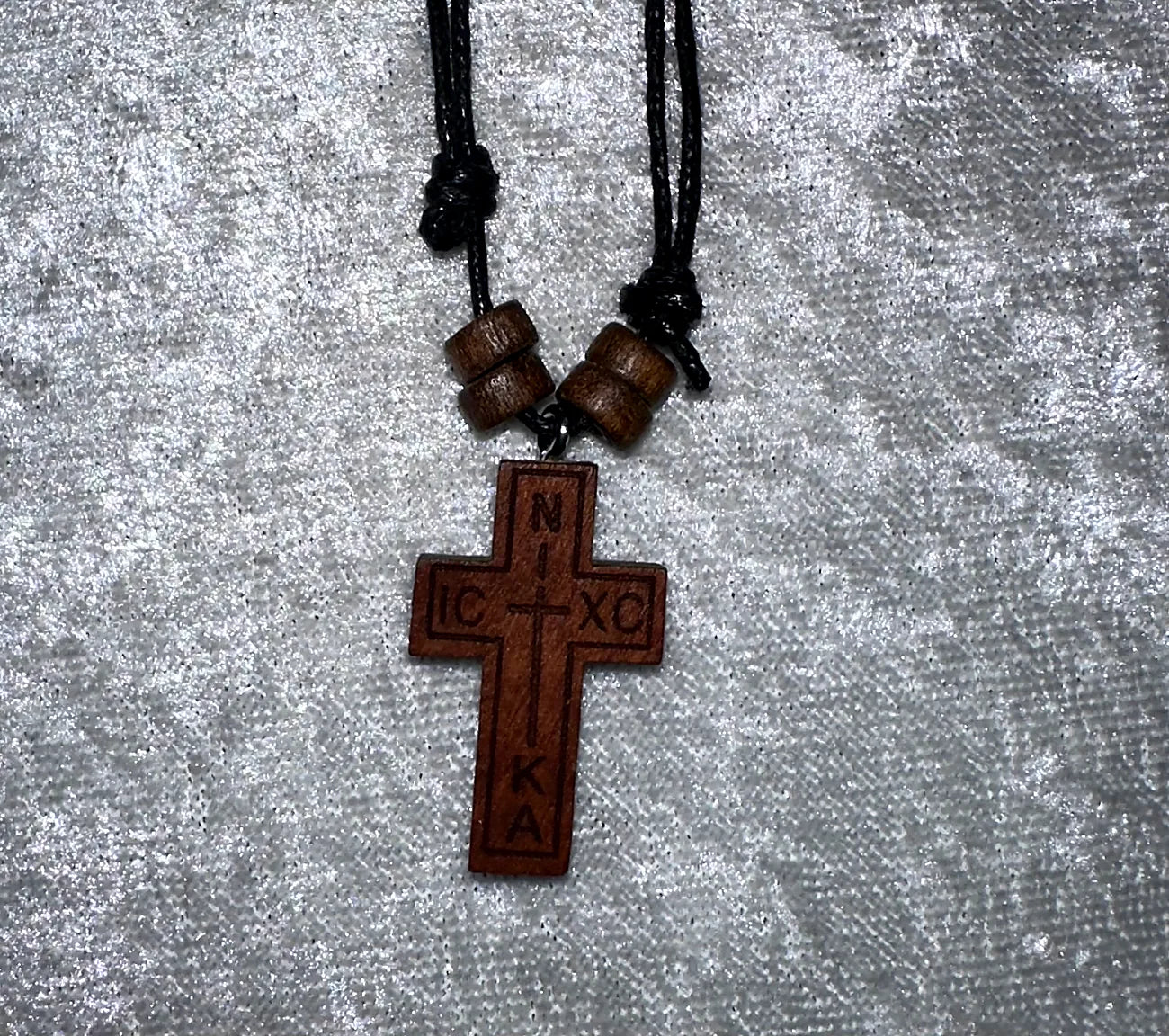 Wooden cross pendant with beads on a gray textured background