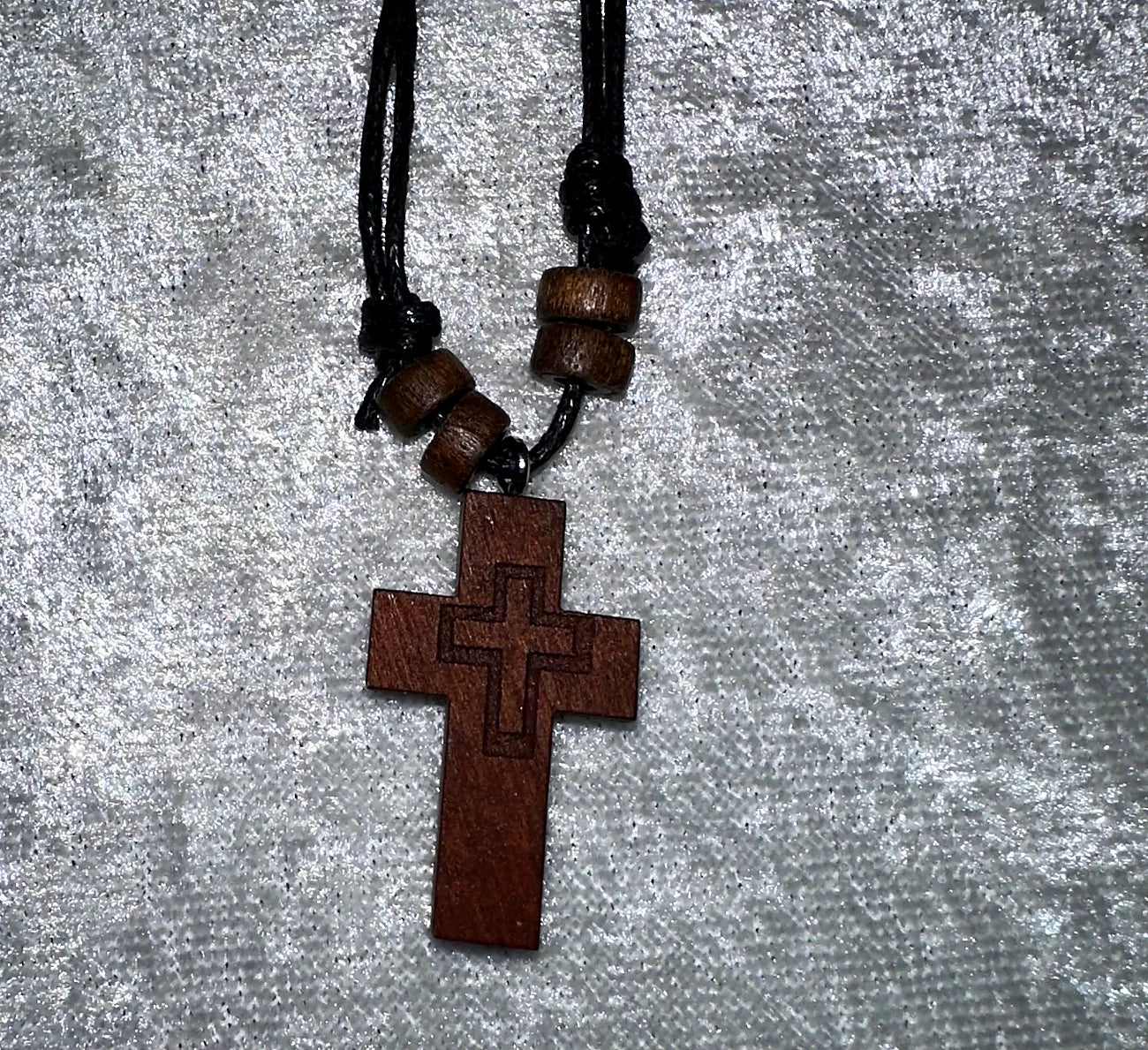 Wooden cross pendant with beads on a gray textured background