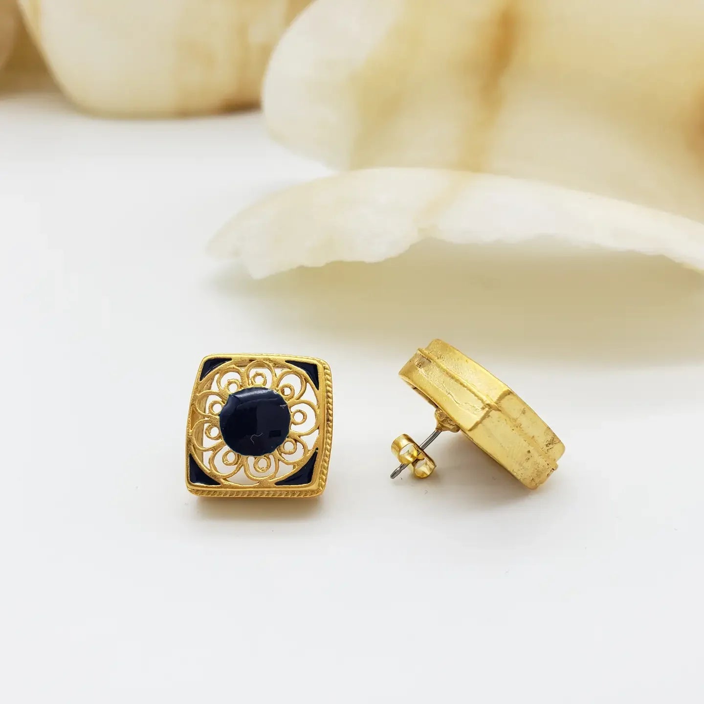 Gold earrings with black gemstones on a white background