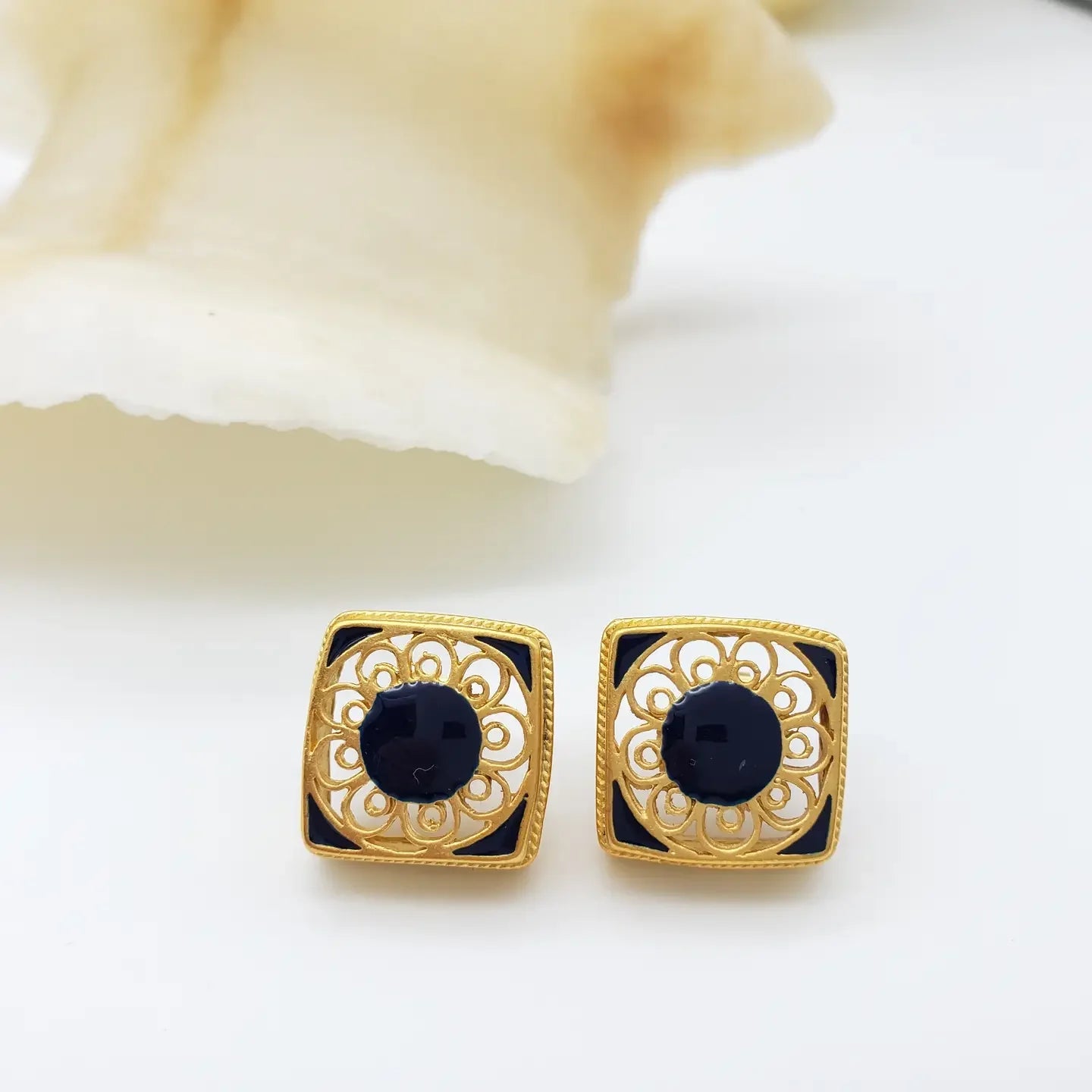 Gold-framed black earrings on a white background
